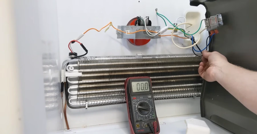 Technician performing voltage test on the refrigerator evaporator fan circuit