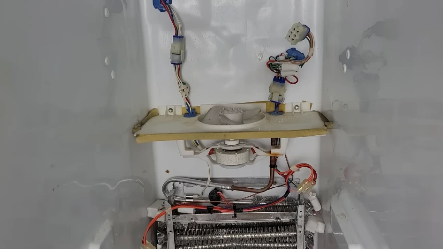 Refrigerator evaporator fan motor and coil assembly behind the freezer back panel