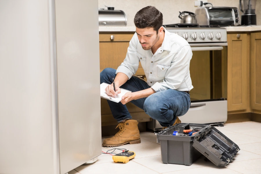 Refrigerator repair technician servicing a residential refrigerator in Concord NC