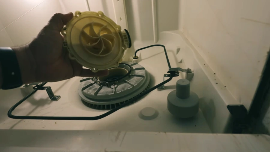 Dishwasher pump impeller being removed during disassembly for inspection and replacement
