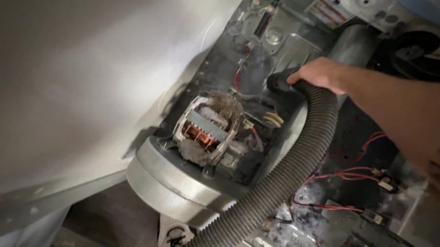 Lint accumulation being cleaned from around the dryer motor