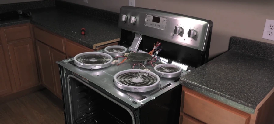 Electric range with cooktop raised for surface burner repair