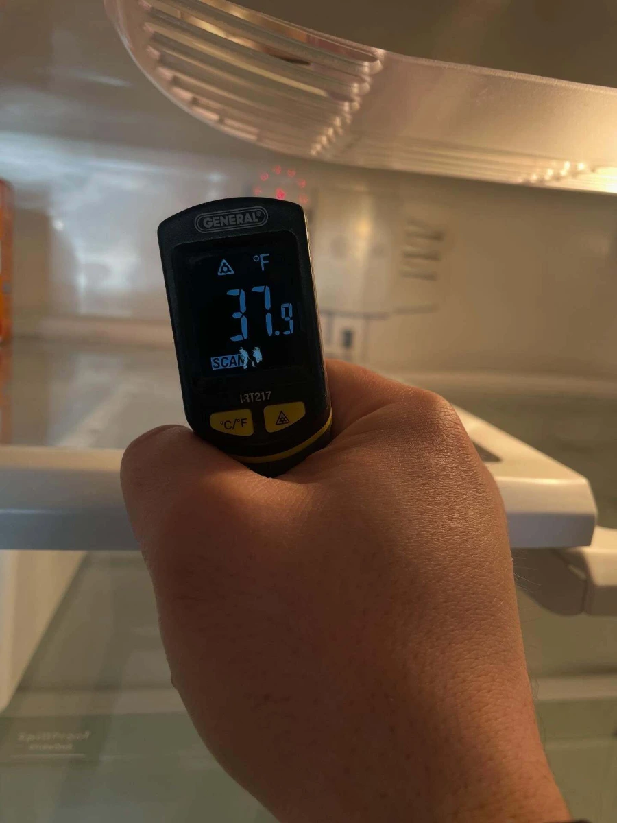 Thermometer measuring temperature inside the fresh food section of a refrigerator at the start of a service call